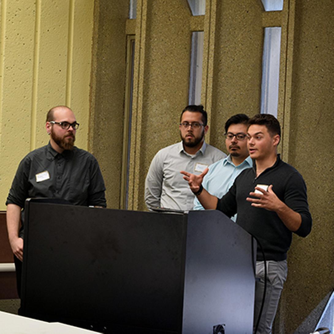 four men giving a presentation
                  