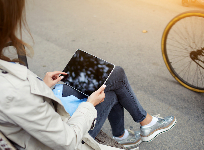 young woman sitting on a bench using a tablet computer