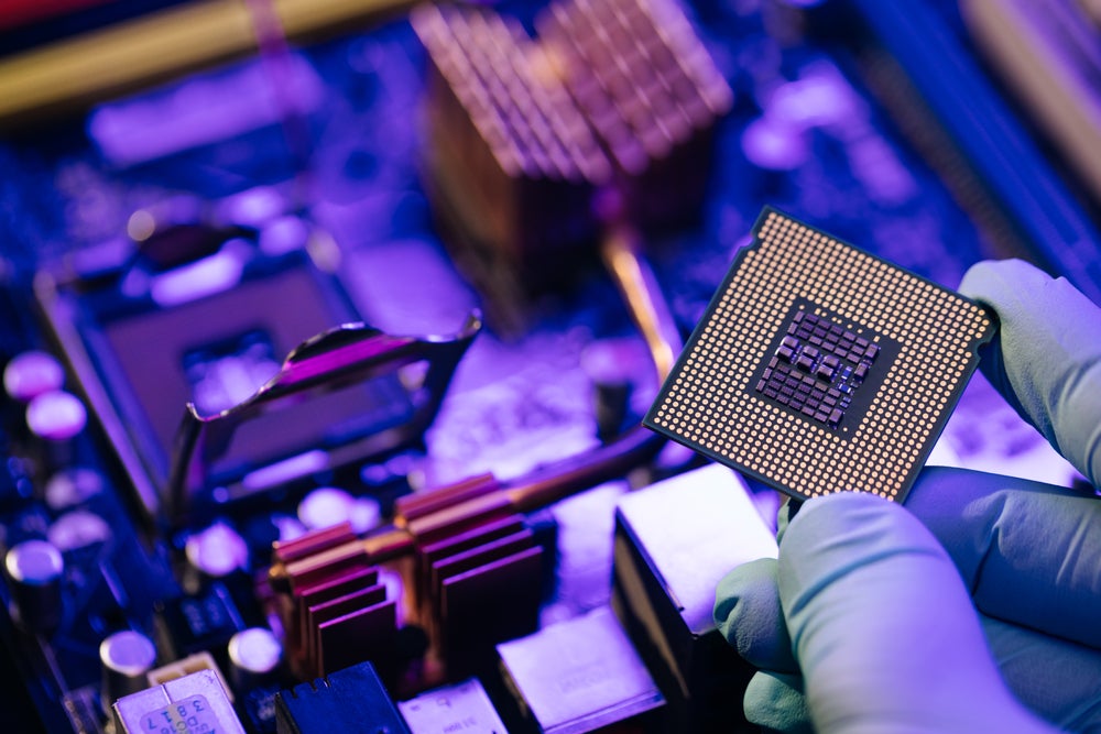 gloved fingers holding a computer chip